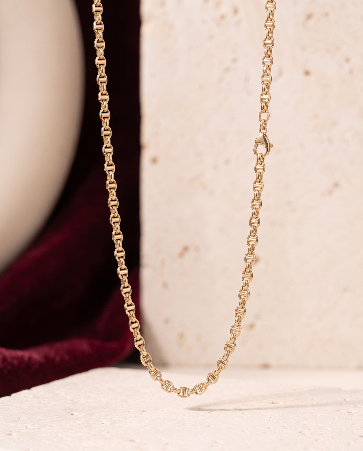 Collana Modulo Gold 18kt sospesa in primo piano, con pietra avorio e velluto bordeaux sfocati